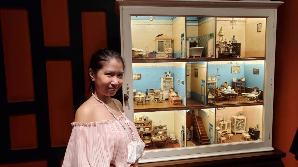 Female visitor standing in front of a traditional Thai ancient-style room display.
